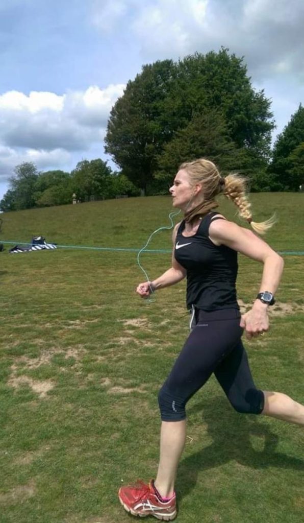 Tall slim woman wearing black gym clothes running on grass