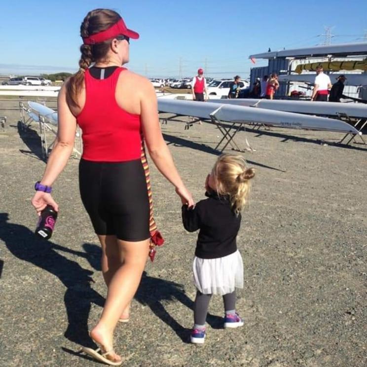 Nicole and young daughter walk across concrete towards a set of boats