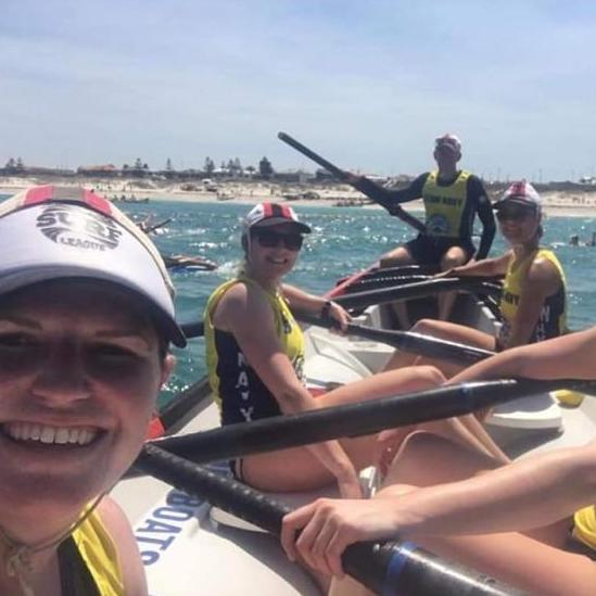Nicole, Kat, and surf league rowing team in a selfie taken on a boat.