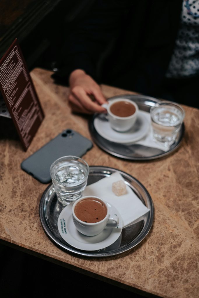 A lady sat in a cafe with two trays of water and tea
